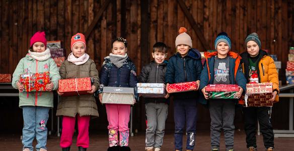 Mehrere Kinder freuen sich über die Weihnachtspäckchen der humedica-Aktion Geschenk mit Herz