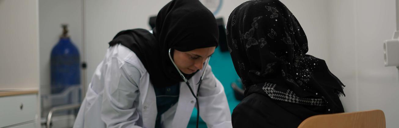 Ärztin untersucht syrische Frau mit einem Stethoskop